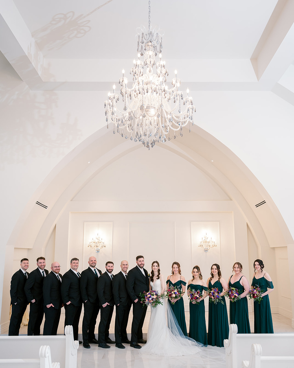 a bride and a groom posing with their entire wedding party in the aria foyer