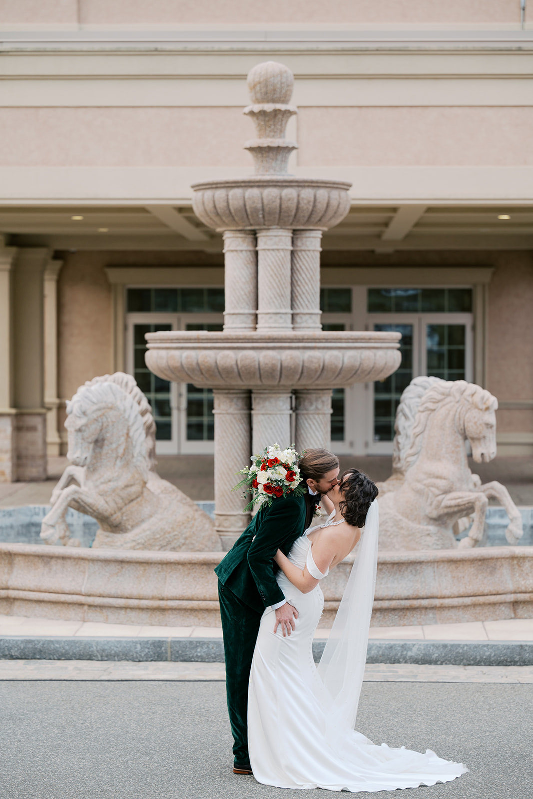 a bride and a groom sharing a kiss outside in front of a fountain