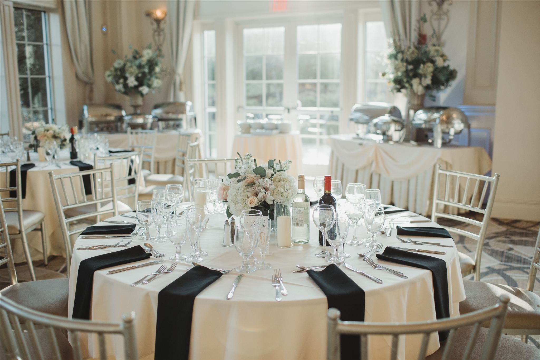 table set for dinner with a white table cloth and black napkins at each seat