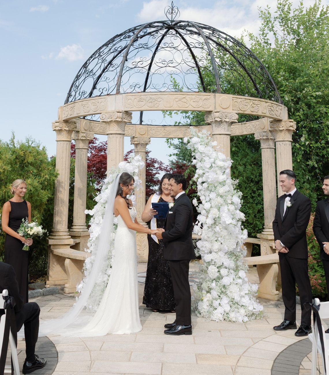 a bride and groom exchanging vows outside in the aria gazebo