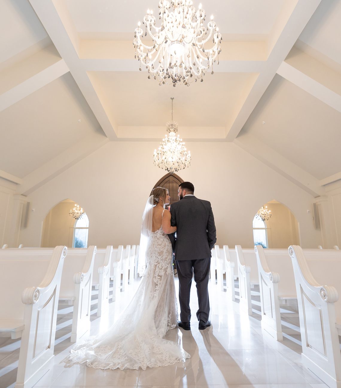 a bride and groom facing away from the camera gazing at each other in the aria chapel