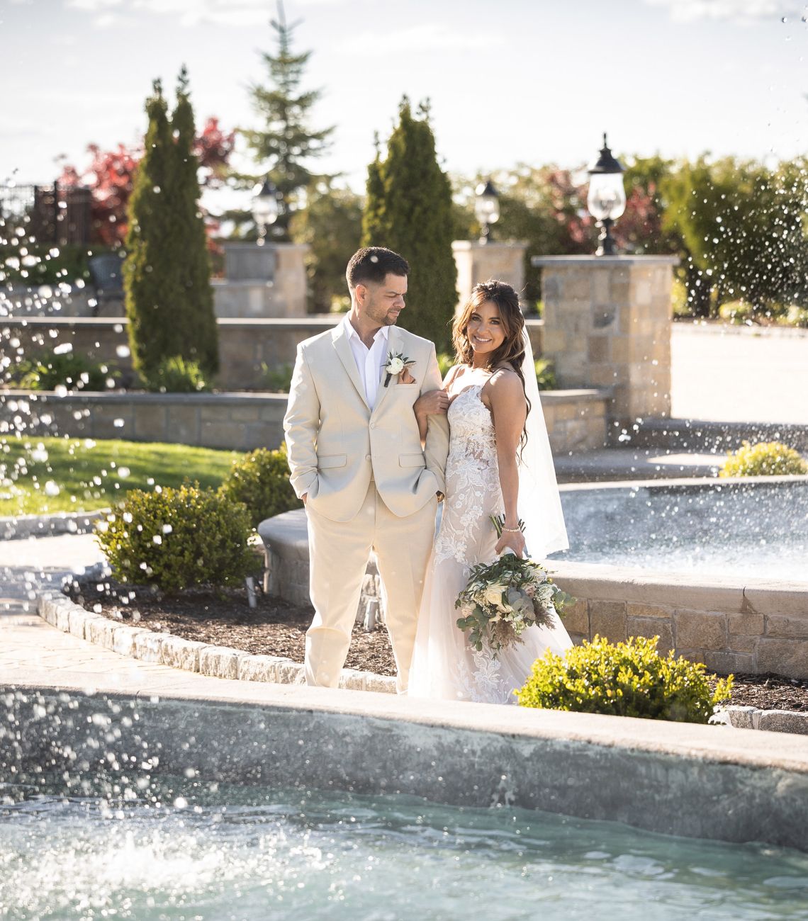 Bride and groom posing together outside near a fountain