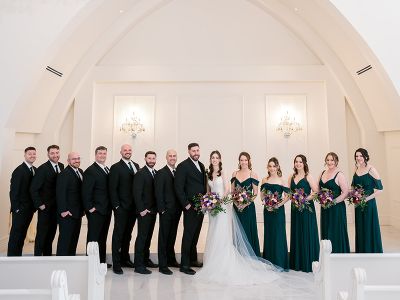 a bride and groom standing the the chapel with the entire wedding party at their sides