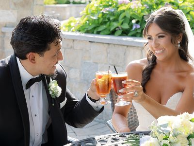 Bride and groom sitting clinking their beverages outside on the patio
