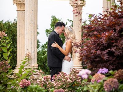 a bride and groom holding each other while outside 