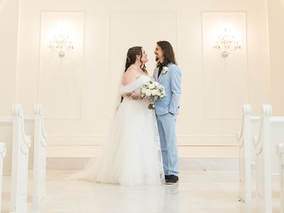 Bride and groom posing in elegant chapel.