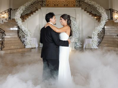 a bride and groom dancing the aria ballroom with clouds of smoke at their feet