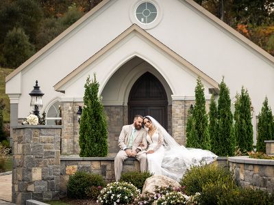 a bride and groom sitting outside the aria chapel