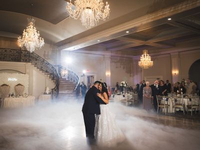 a bride and groom sharing their first dance with clouds of smoke at their feet