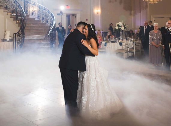 bride and groom sharing their first dance in the aria ballroom with clouds of smoke at their feet