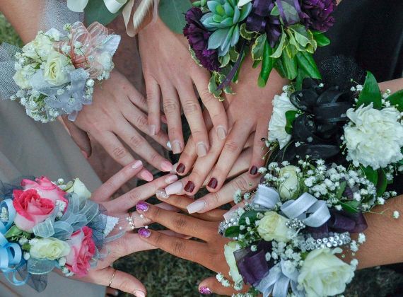 
A group of girl's hands together with corsages on their wrists for prom