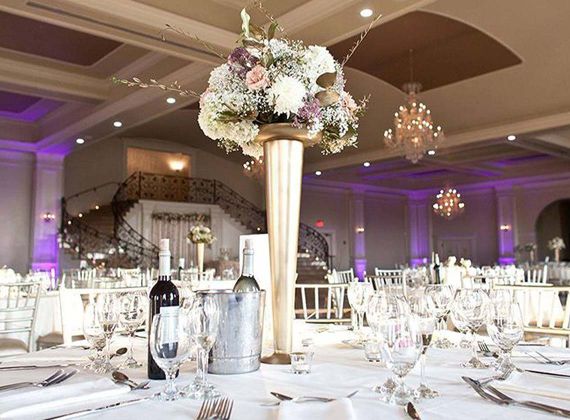 Aria ballroom filled with round tables with table setting under magenta lighting
